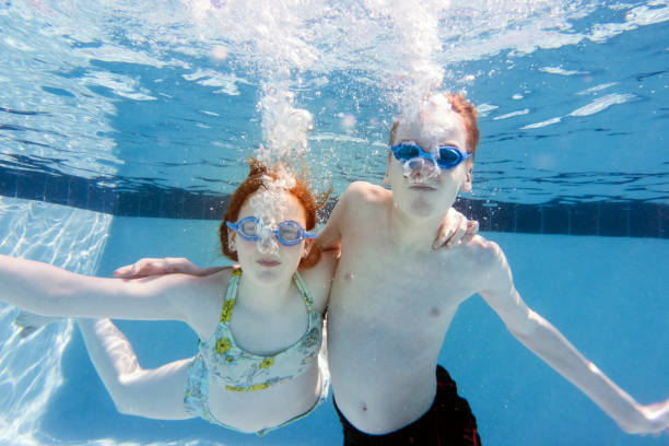 istock Brother and sister swimming underwater in pool 1045249090