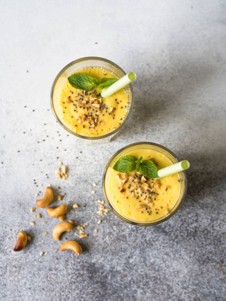 Smoothies of mango, yogurt and cashew in glasses on a gray background stock photo