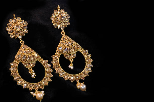 istock Fancy designer golden earring set closeup macro image on black background 1045257716