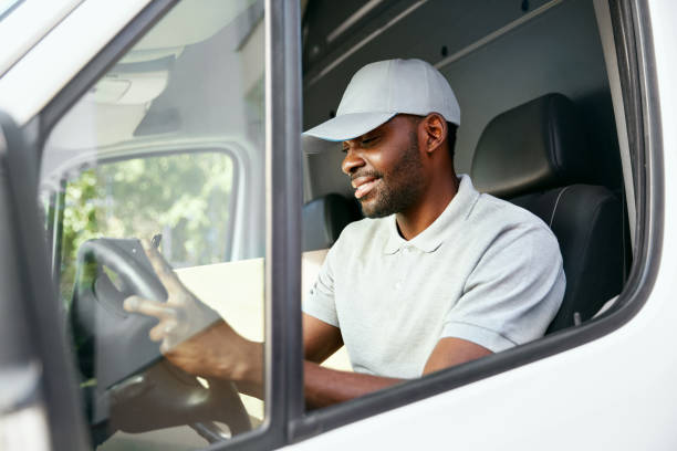 istock Courier. Delivery Man Reading Addresses Sitting In Delivery Van 1045265584