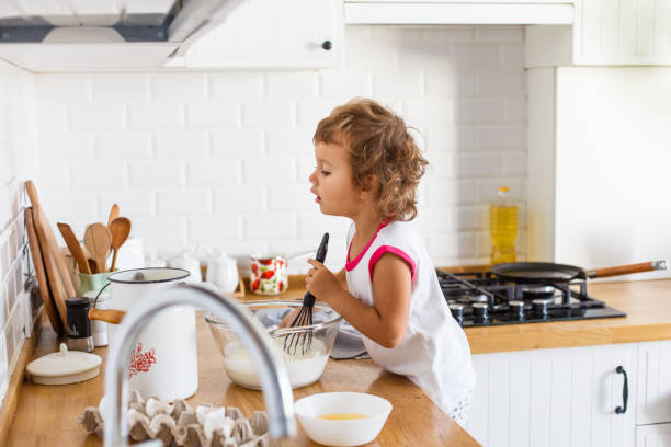 istock 3 years cute girl preparing dough for pancakes at the kitchen. 1045266872