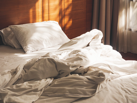 Cama colchón almohadas Duvet deshecha dormitorio mañana con luz del sol interior dormitorio photo