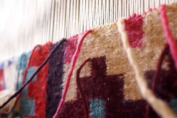 Close up of wool on a loom, weaving a carpet