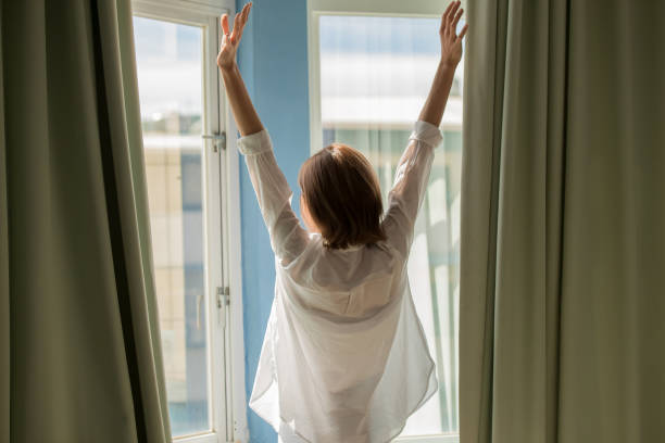 istock woman opening curtains 1045279176