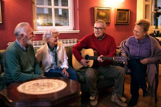 istock Old senior man playing guitar with his friends, making great party 1045279488