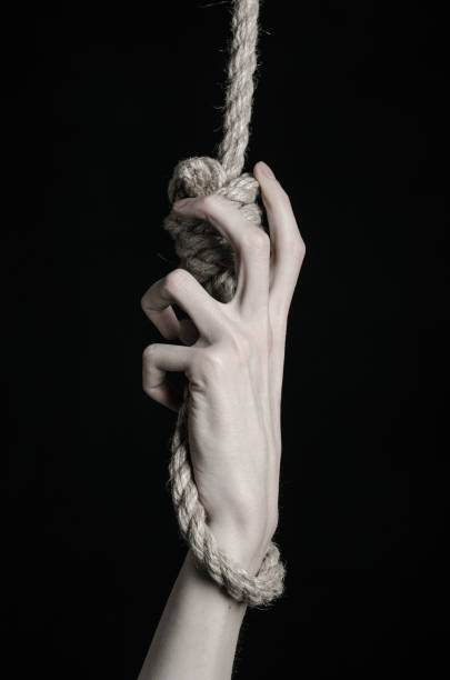 istock Suicide and depression topic: human hand hanging on rope loop on a black background 1045279618