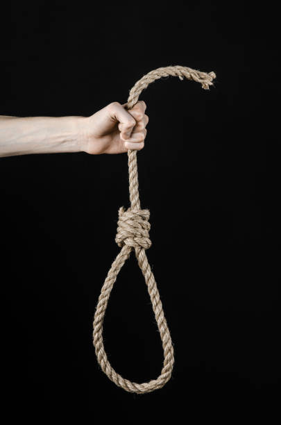 istock Lynching and suicide theme: man's hand holding a loop of rope for hanging on black isolated background 1045279744