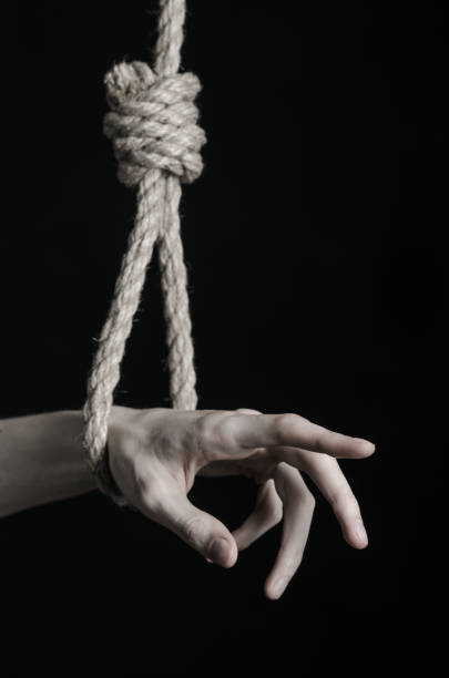 istock Suicide and depression topic: human hand hanging on rope loop on a black background 1045279774