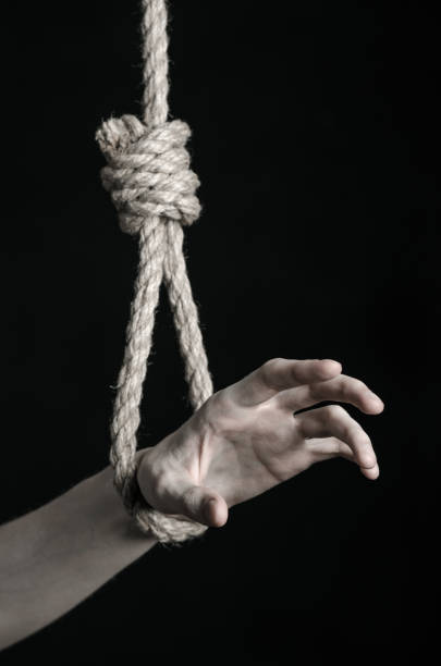 istock Suicide and depression topic: human hand hanging on rope loop on a black background 1045282682