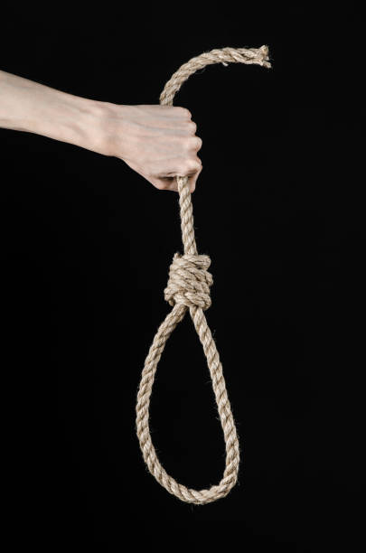 istock Lynching and suicide theme: man's hand holding a loop of rope for hanging on black isolated background 1045282704