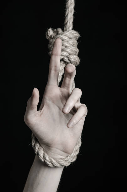 istock Suicide and depression topic: human hand hanging on rope loop on a black background 1045283504