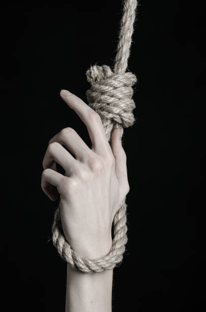 istock Suicide and depression topic: human hand hanging on rope loop on a black background 1045283540