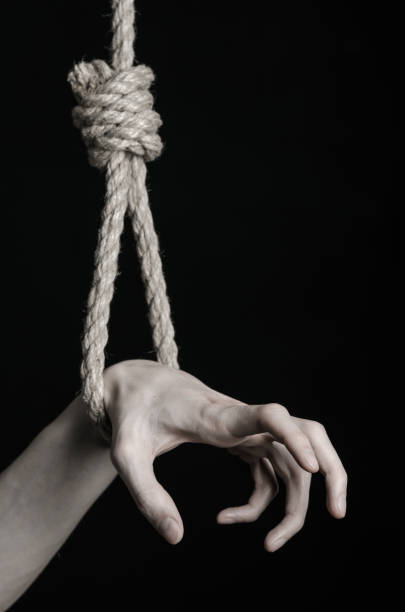 istock Suicide and depression topic: human hand hanging on rope loop on a black background 1045283724