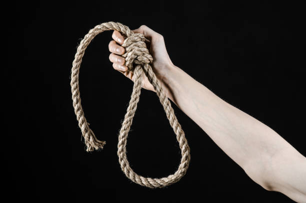 istock Lynching and suicide theme: man's hand holding a loop of rope for hanging on black isolated background 1045283750