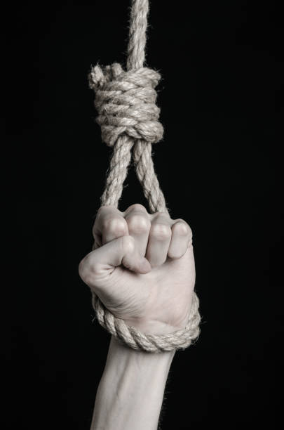 istock Suicide and depression topic: human hand hanging on rope loop on a black background 1045283926