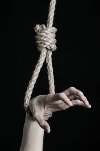 istock Suicide and depression topic: human hand hanging on rope loop on a black background 1045285902