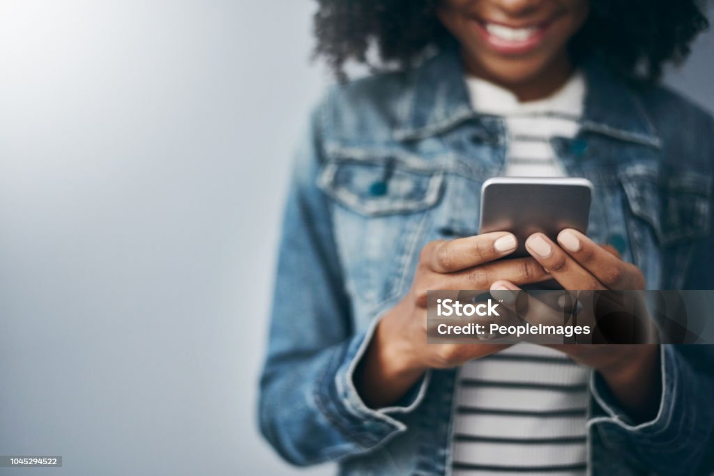 She loves being connected Studio shot of an unrecognizable young woman using her cellphone against a grey background Social Media Stock Photo