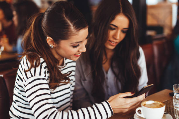 istock Two young women looking in smartphone screen in cafe 1045297164
