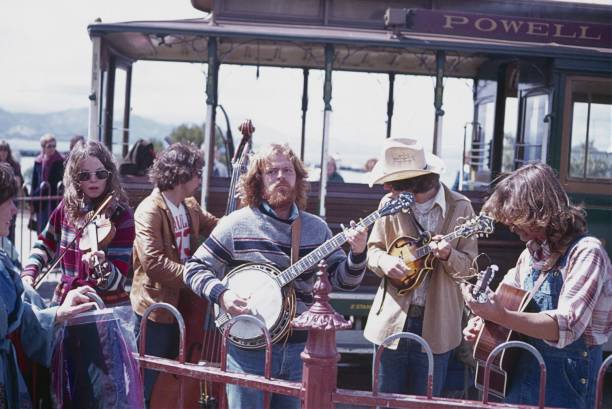 Hippie band plays at a cable car stop in San Francisco San Francisco, California, USA, 1977. Hippie band plays at a cable car stop in St. Francisco in front of locals and tourists. performance group photos stock pictures, royalty-free photos & images