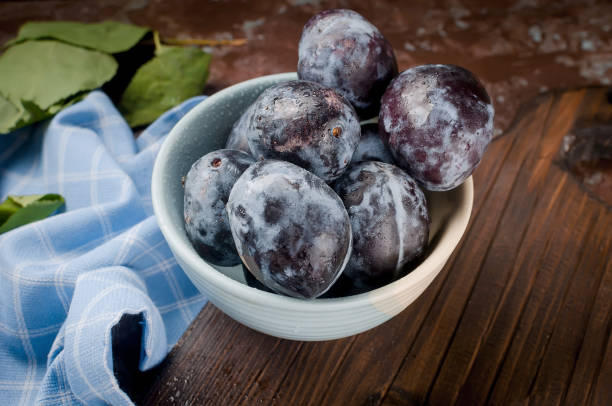 istock Plums in a pottery bowl on dark rustic wood 1045301470