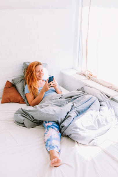 istock Young woman using smartphone in bed 1045306628