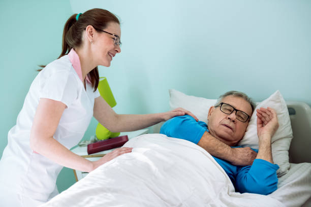 istock Nice smiling nurse looking at patient who sleeping and dreaming 1045306852