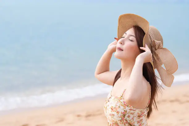 Young Asian woman with hat enjoying at the beach. Summer,vacation and holiday concept
