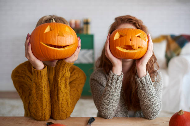 duas mulheres mostrando abóboras de halloween - entalhe - fotografias e filmes do acervo