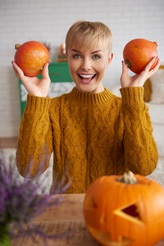 Portrait of cheerful woman holding two pumpkins