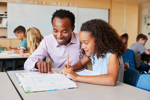 istock Teacher working with elementary school girl at her desk 1045322176