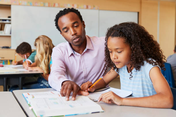 istock Teacher working with elementary school girl at her desk 1045322212