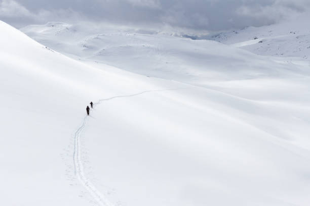 istock Two people ski touring beautiful vast white mountain side 1045322220