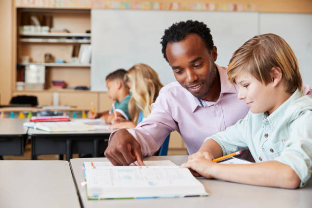 istock Teacher working with elementary school boy at his desk 1045322344