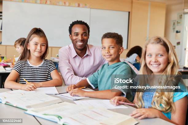 Insegnante Di Scuola Maschile E Bambini In Classe Sorridenti Alla Macchina Fotografica - Fotografie stock e altre immagini di Insegnante