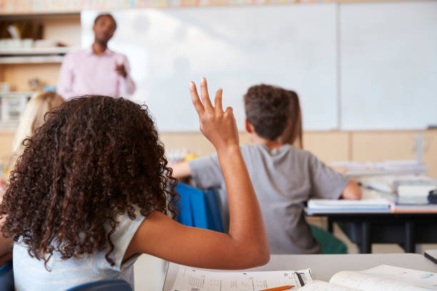 istock Girl raising hand to answer in an elementary school class 1045322644