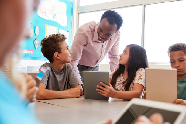 istock Teacher among kids with computers in elementary school class 1045327684
