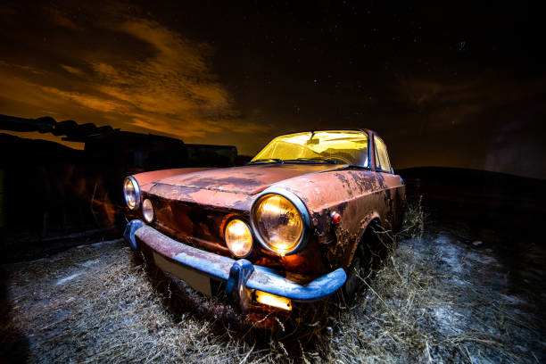 Ancient car abandoned in the countryside and illuminated with lanterns