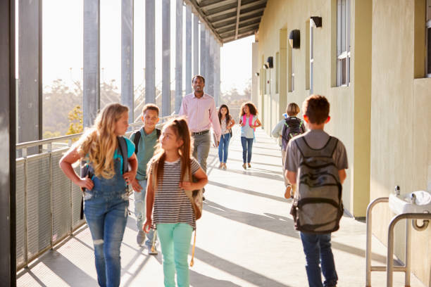 istock Male teacher and  pupils walking on school campus 1045328650