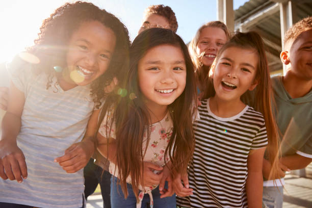 i bambini delle scuole elementari sorridono alla telecamera al momento della pausa - school age girl foto e immagini stock