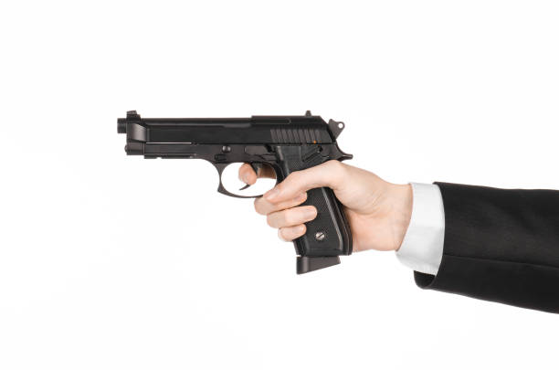 istock Firearms and security topic: a man in a black suit holding a gun on an isolated white background in studio 1045331678