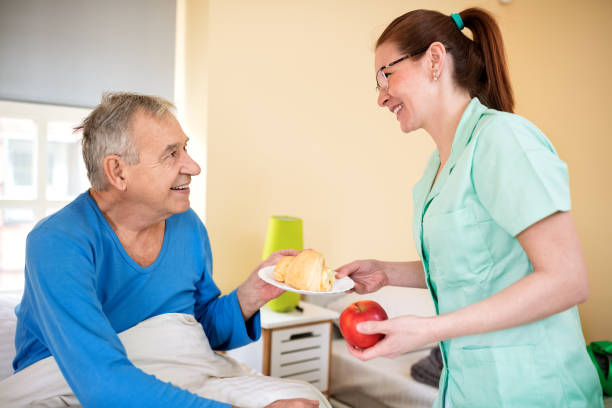 istock Happy old senior man looking at careful nurse 1045331938