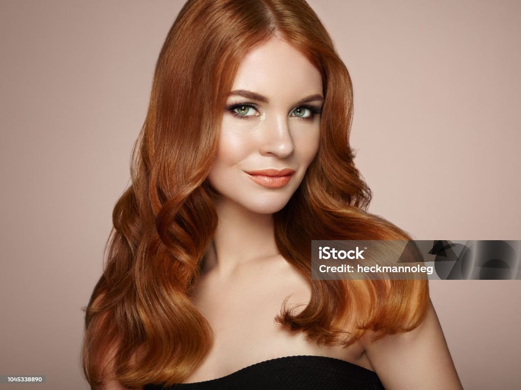 Redhead woman with curly hair Redhead Girl with Long Healthy and Shiny Curly Hair. Care and Beauty. Beautiful Model Woman with Wavy Hairstyle. Make-Up and Black Dress Redhead Stock Photo