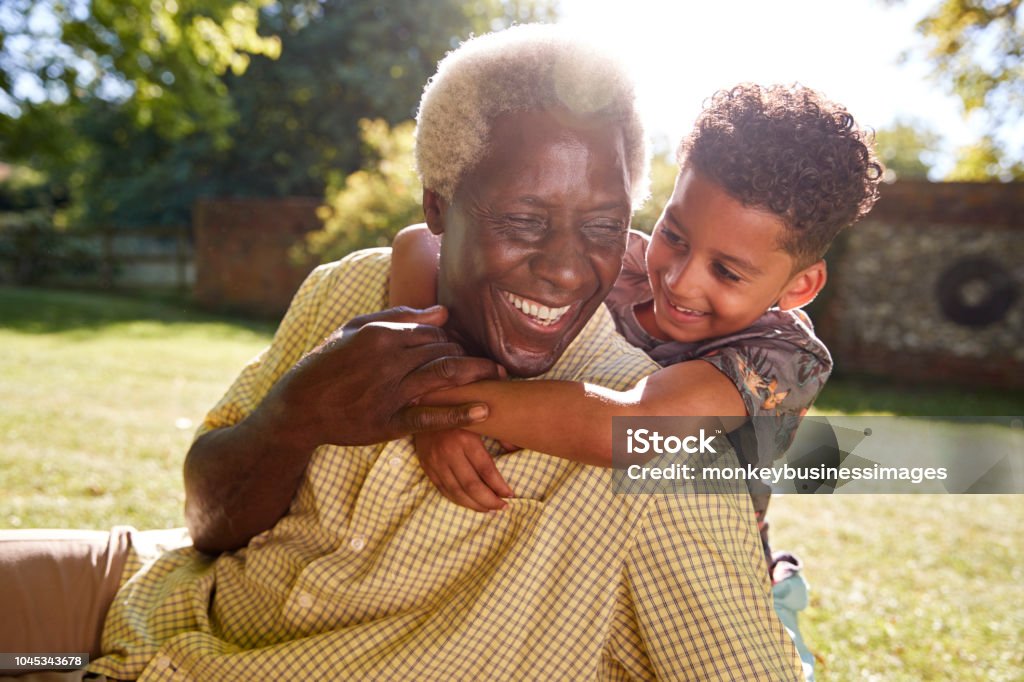 Senior schwarzer Mann sitzen auf dem Rasen, umgeben von seinem Enkel - Lizenzfrei Alter Erwachsener Stock-Foto