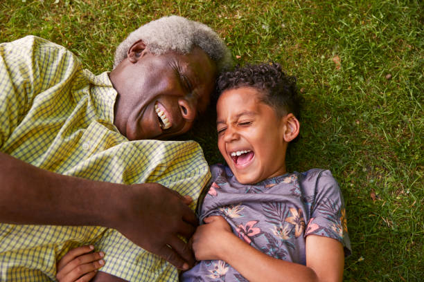 istock Laughing boy and granddad lying on grass, overhead close up 1045343698