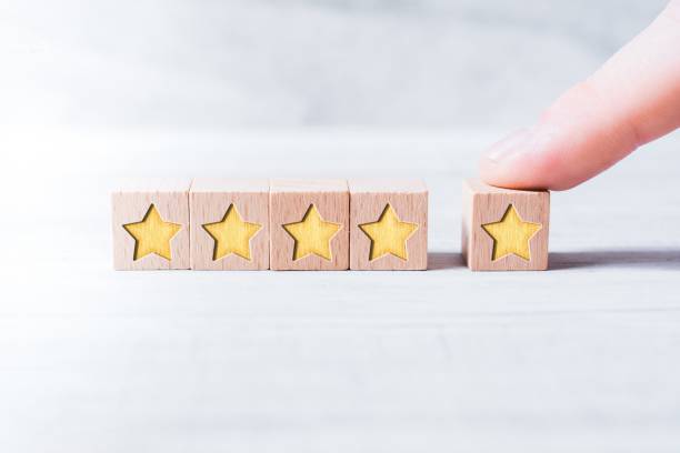 5 Star Ranking Formed By Wooden Blocks And Arranged By A Male Finger On A White Table stock photo