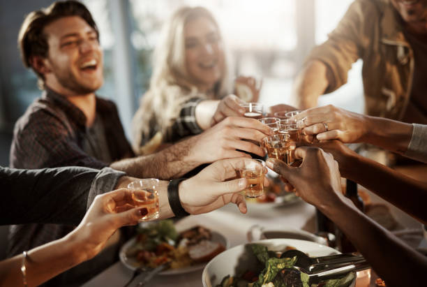 Friends know how to have fun Shot of a group of young friends making a toast at a dinner party shot glass stock pictures, royalty-free photos & images