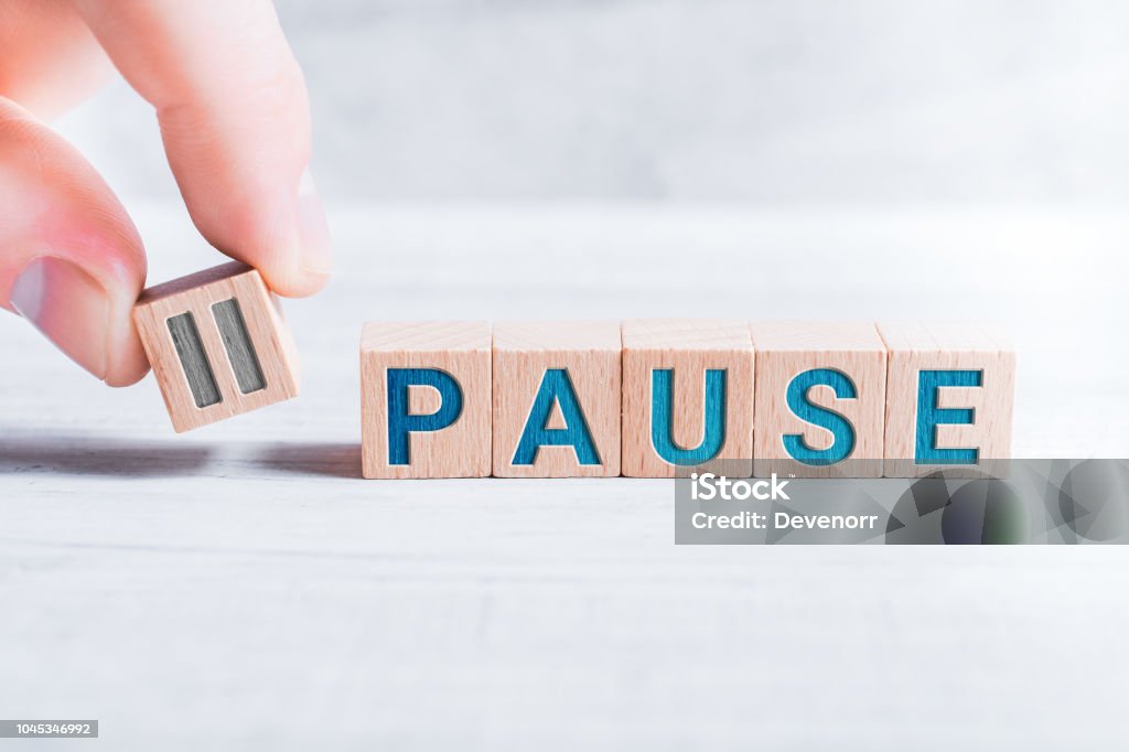 The Word Pause Formed By Wooden Blocks And Arranged By Male Fingers On A White Table The Word Pause Formed By Wooden Blocks And Arranged By Male Fingers On White Table Resting Stock Photo