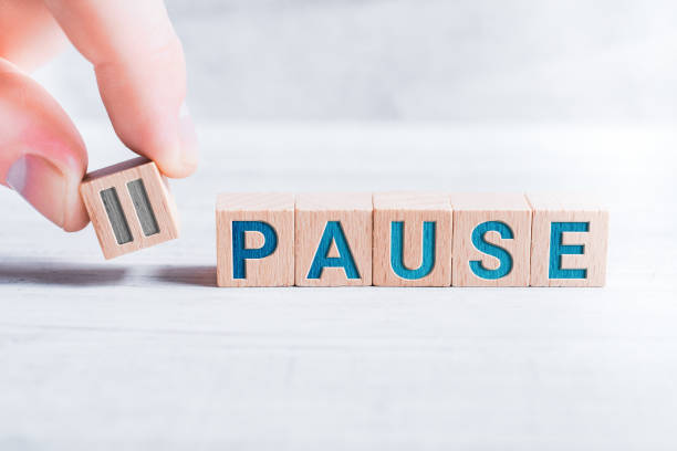 The Word Pause Formed By Wooden Blocks And Arranged By Male Fingers On A White Table stock photo