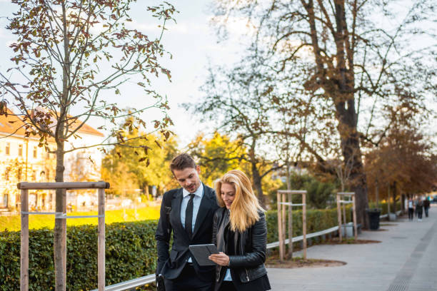 istock Businesspeople using a digital tablet and walking in the park 1045348008