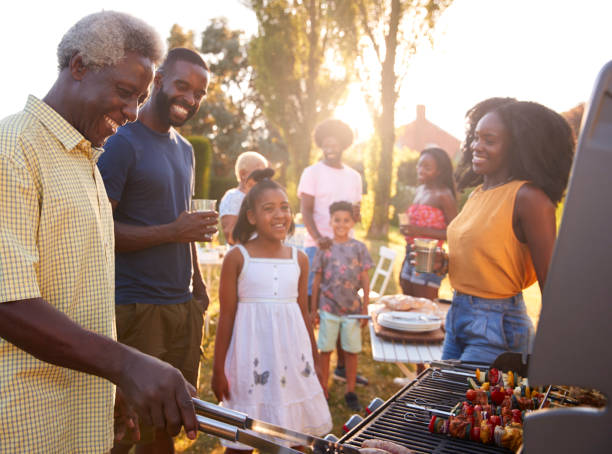 Multi generation black family barbecue, grandad grilling Multi generation black family barbecue, grandad grilling grilled stock pictures, royalty-free photos & images